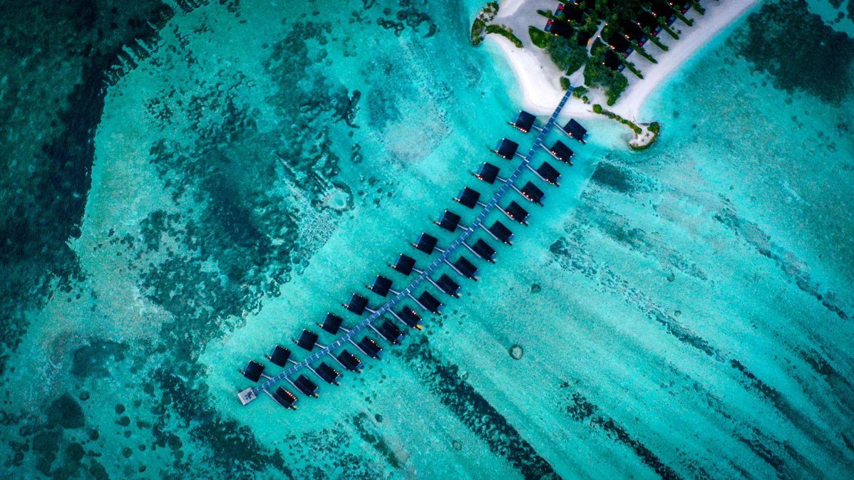 Aerial view of luxury overwater villas in the Maldives with turquoise lagoon and tropical island resort